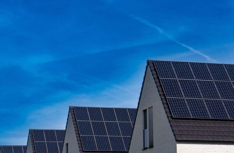 Painéis solares instalados nos telhados de casas residenciais sob céu azul.